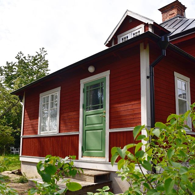 Röd farstukvist med vita träfönster med fasta spröjs och grön trädörr