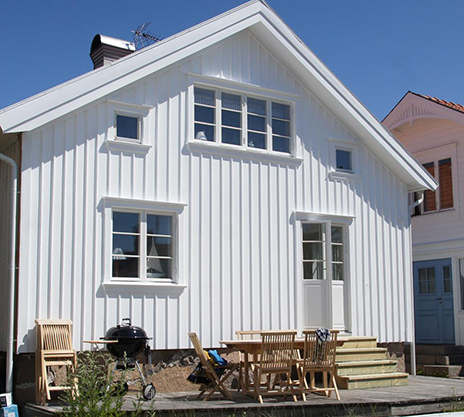 Vit hus fotat från gaveln med träfönster och fönsterdörrar