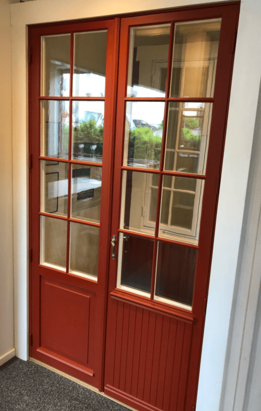 Röd farstukvist med vita träfönster med fasta spröjs och grön trädörr